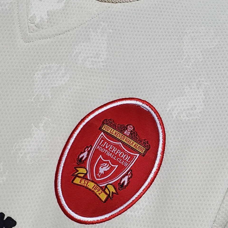 Liverpool retro bortatröja 1996/97, närbild på rött ovalt klubbmärke med You’ll Never Walk Alone och Est. 1892