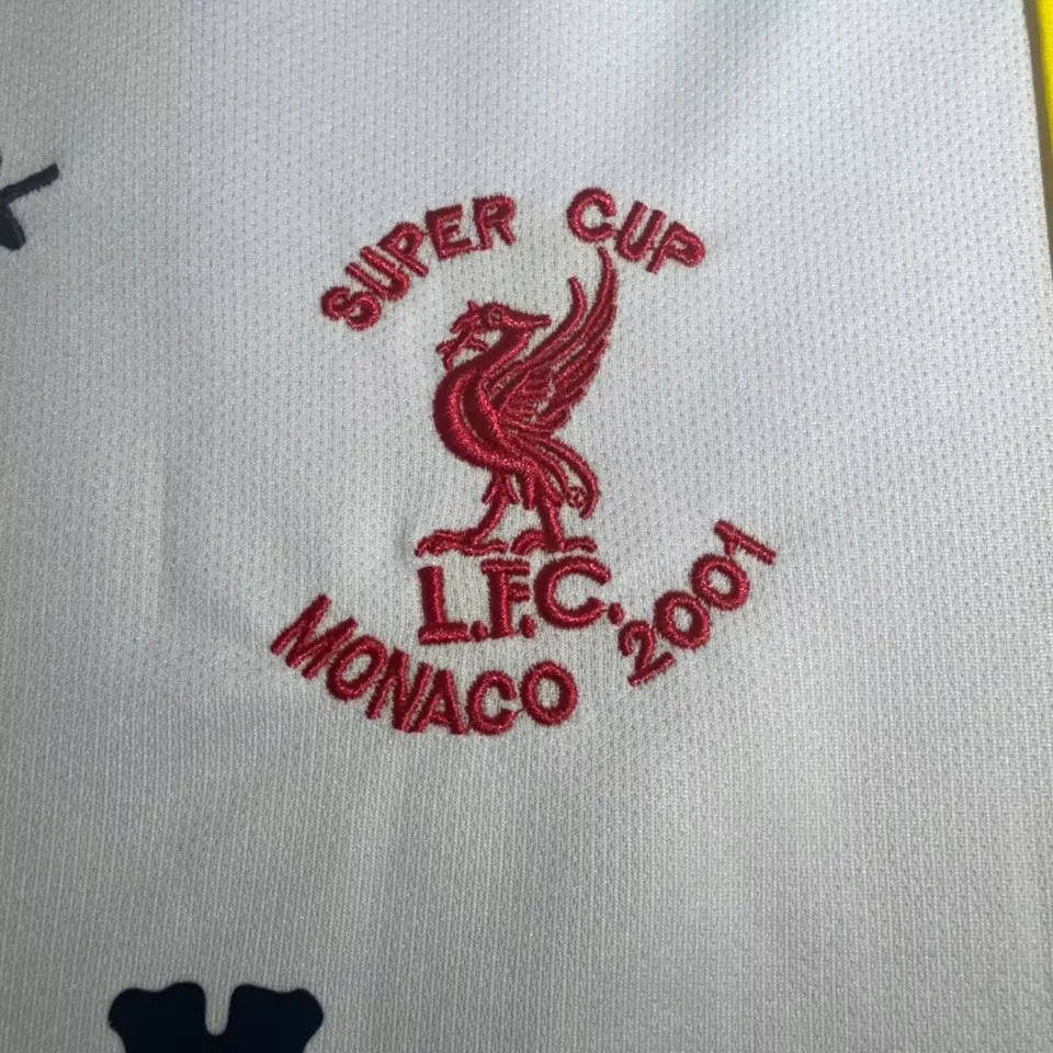 Liverpool retro bortatröja 2001/02, närbild på rött broderi med leverfågel och texten Super Cup L.F.C. Monaco 2001