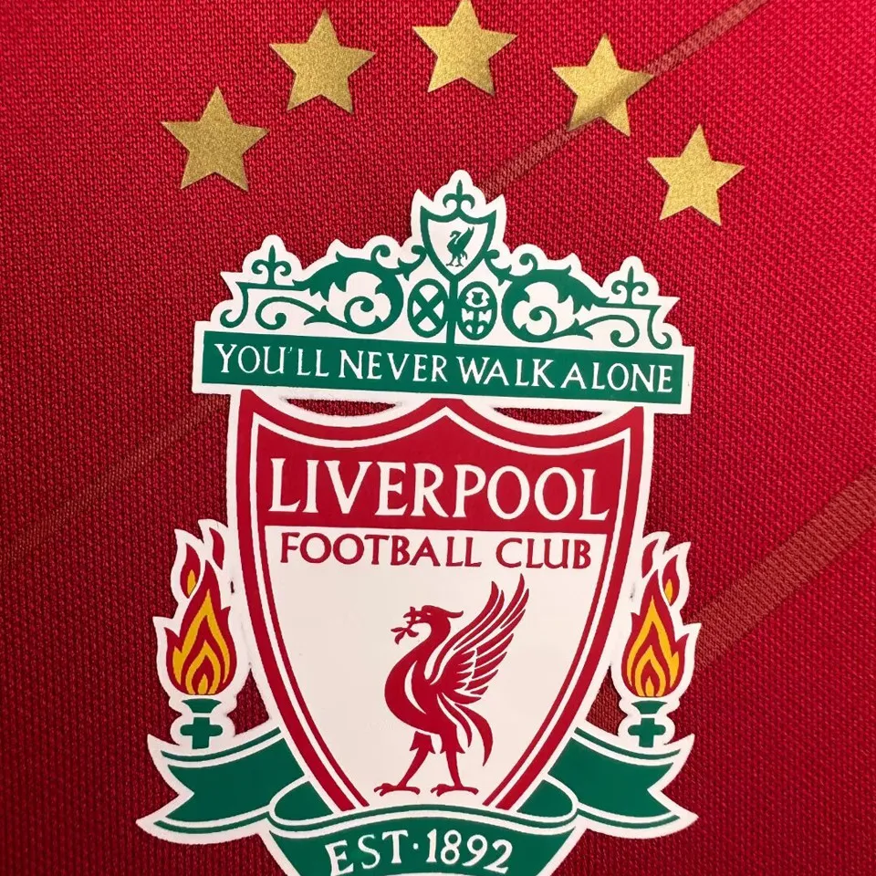 Liverpool retro hemmatröja 2005/06, närbild på klubbmärke med fem guldstjärnor och You’ll Never Walk Alone