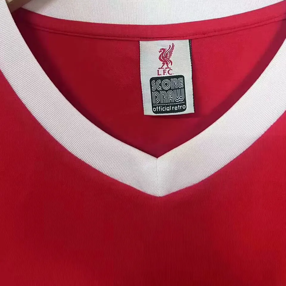 Liverpool retrotröja 1979 hemma, vinklad bild på V-krage, märke och vit ärmkant